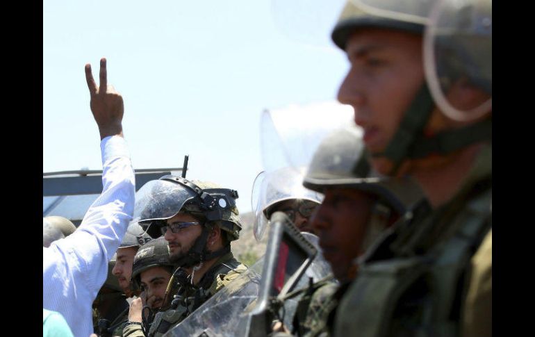 Un manifestante hace el gesto de la victoria ante soldados israelíes durante una protesta para apoyar a los presos. EFE / A. Badarneh